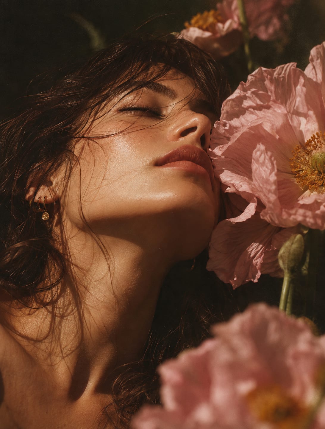 A woman's face bathed in warm light among cosmos flowers